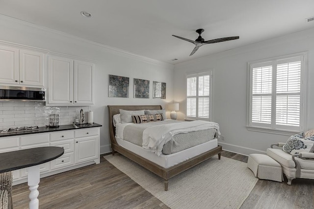 bedroom with ceiling fan, wood finished floors, visible vents, baseboards, and crown molding