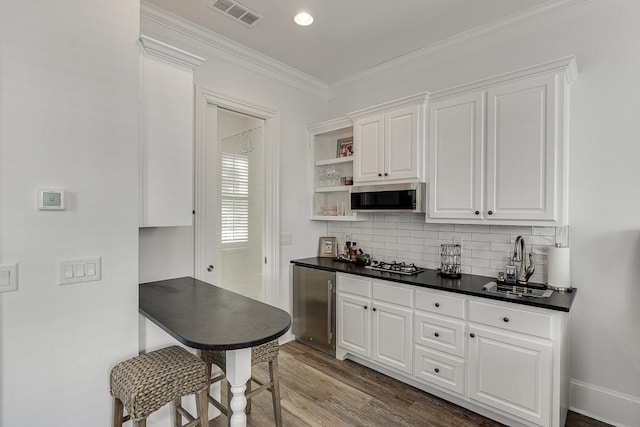 kitchen with visible vents, dark countertops, stainless steel appliances, crown molding, and a sink