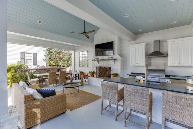 kitchen featuring a large fireplace, wall chimney exhaust hood, dark countertops, and finished concrete floors