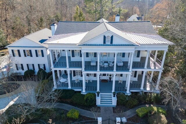 view of front of home featuring covered porch, a chimney, stairs, and a balcony