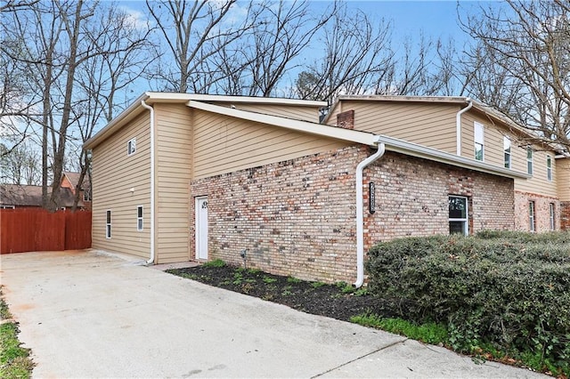 view of side of home featuring fence and brick siding