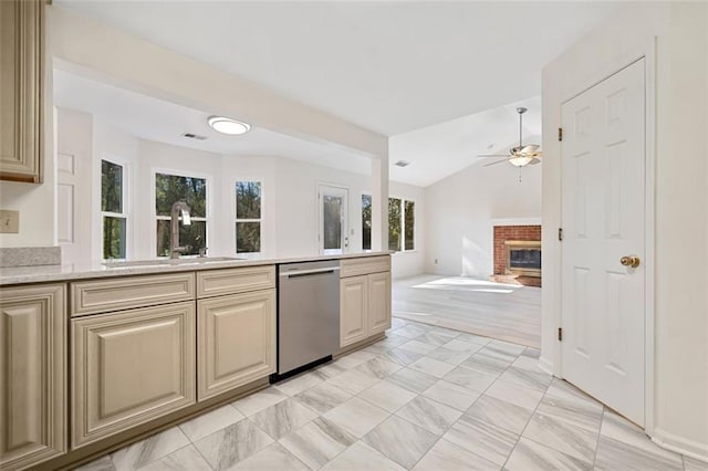 kitchen with dishwasher, lofted ceiling, ceiling fan, sink, and a brick fireplace