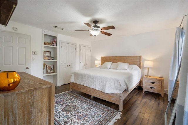 bedroom featuring multiple closets, ceiling fan, and dark wood-type flooring