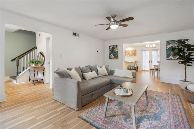 living room featuring ceiling fan with notable chandelier, french doors, and light hardwood / wood-style flooring