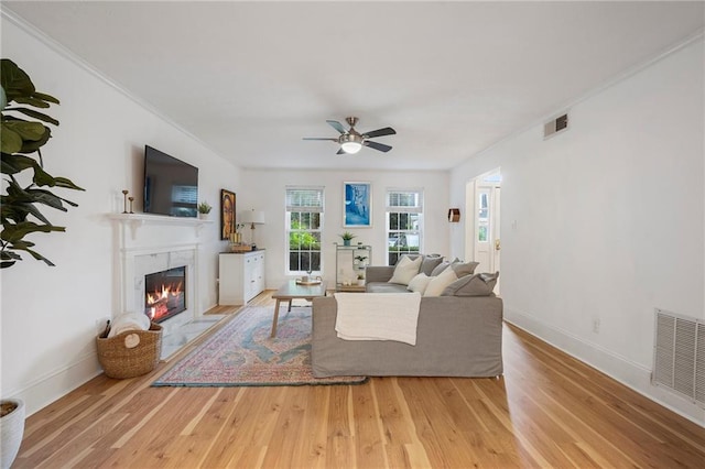 living room featuring ceiling fan, crown molding, and light hardwood / wood-style floors