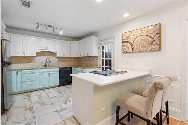 kitchen with white cabinetry, tasteful backsplash, kitchen peninsula, a breakfast bar, and black appliances