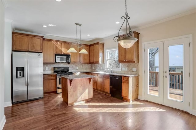 kitchen featuring french doors, hanging light fixtures, stainless steel appliances, a kitchen island, and ornamental molding