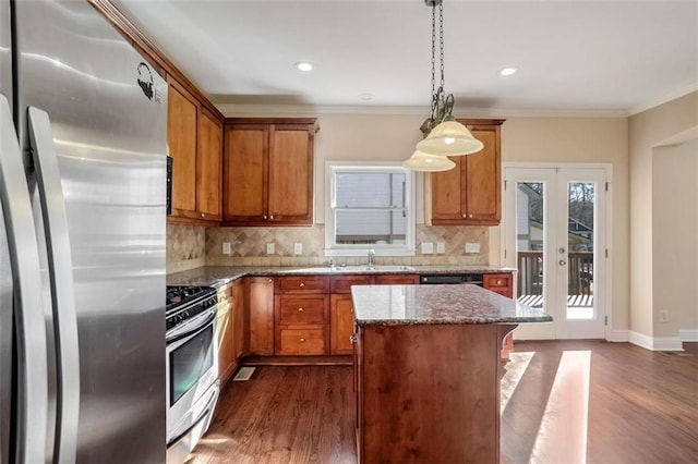 kitchen with a center island, hanging light fixtures, ornamental molding, stone countertops, and stainless steel appliances