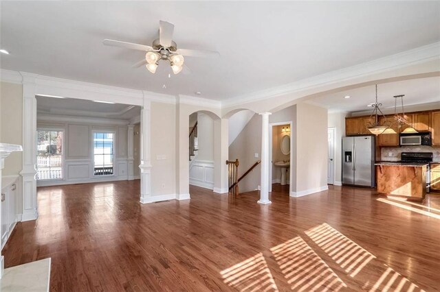 unfurnished bedroom featuring ensuite bath, ceiling fan, a raised ceiling, light colored carpet, and ornamental molding