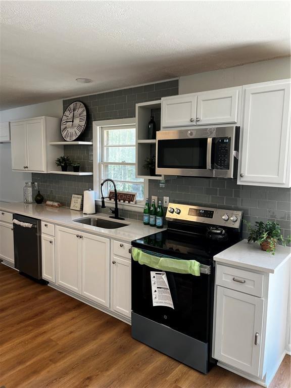 4103 Laynewood Cir, Tucker, GA 30084 - kitchen with stainless steel appliances, open shelves, white cabinets, dark wood-type flooring, and backsplash