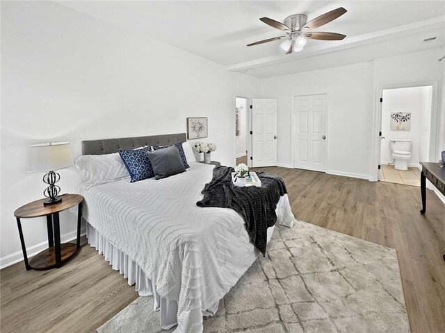 bedroom with ensuite bath, ceiling fan, baseboards, and wood finished floors