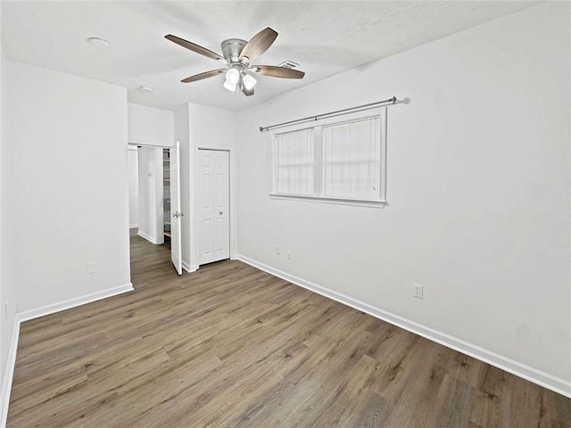 unfurnished bedroom featuring baseboards, a ceiling fan, a closet, and wood finished floors