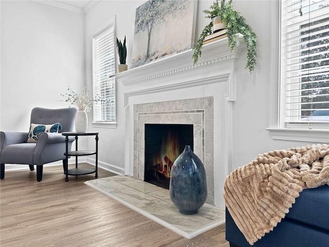 sitting room featuring a fireplace, crown molding, a healthy amount of sunlight, and wood finished floors