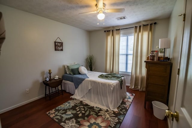 bedroom featuring dark wood-style flooring, a textured ceiling, baseboards, and ceiling fan