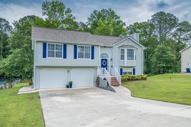 bi-level home featuring a chimney, driveway, a garage, and a front lawn