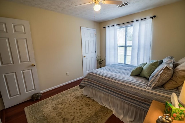 bedroom with baseboards, dark wood-style floors, a ceiling fan, and a textured ceiling