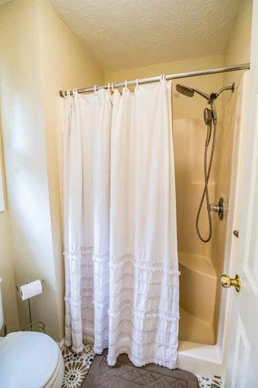 bathroom featuring a shower with shower curtain, toilet, and a textured ceiling