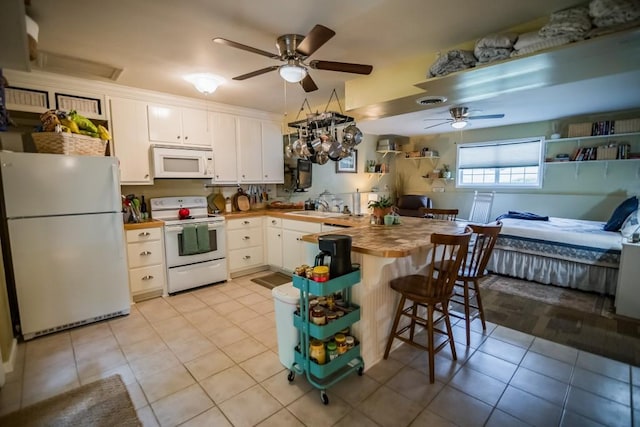 kitchen with white appliances, butcher block counters, ceiling fan, white cabinetry, and a peninsula