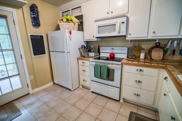 kitchen with white appliances, white cabinets, tile countertops, and light tile patterned flooring