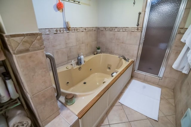 full bath featuring a shower stall, tile walls, a tub with jets, wainscoting, and tile patterned floors