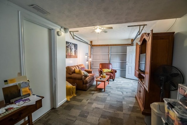 living area with dark colored carpet, a ceiling fan, and a garage