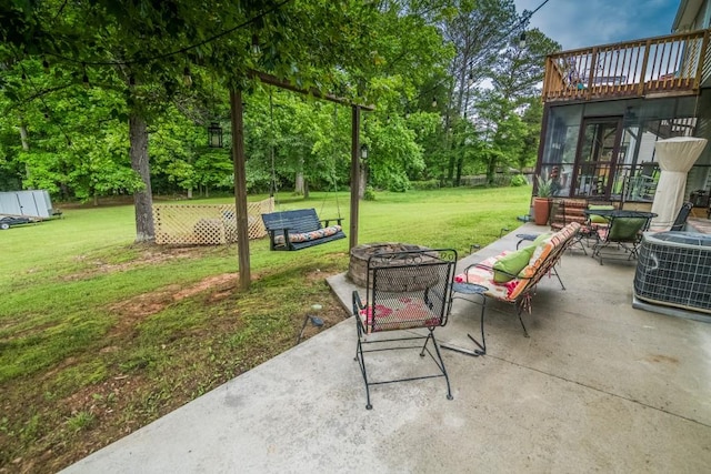 view of patio / terrace with a fire pit, central AC, a sunroom, and view of wooded area