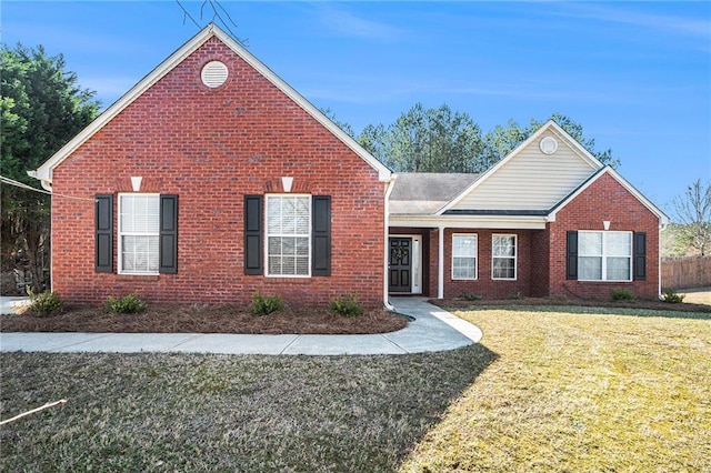 view of front of house with brick siding, a front lawn, and fence