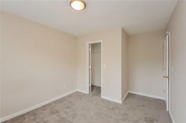 unfurnished bedroom featuring a spacious closet, light colored carpet, a closet, and baseboards