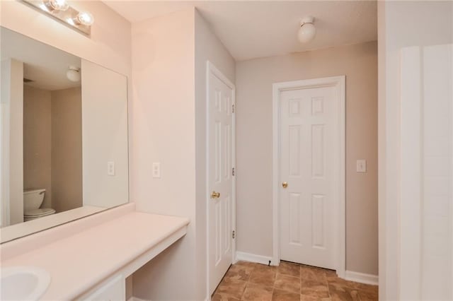 bathroom with baseboards, vanity, and toilet