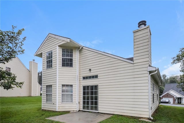 back of house with a patio, a lawn, and a chimney