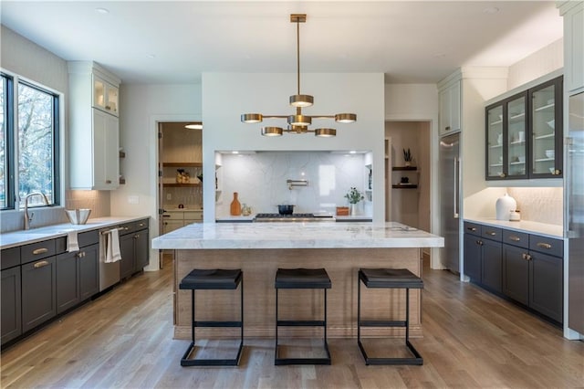 kitchen with appliances with stainless steel finishes, a breakfast bar area, a sink, and light wood finished floors