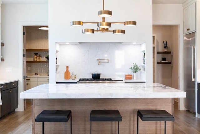 kitchen with light stone counters, wood finished floors, a kitchen breakfast bar, range, and decorative backsplash