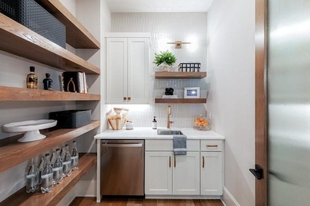 bar with decorative backsplash, baseboards, dishwasher, and a sink