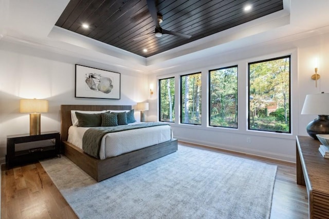 bedroom with wood finished floors, a raised ceiling, wood ceiling, and baseboards