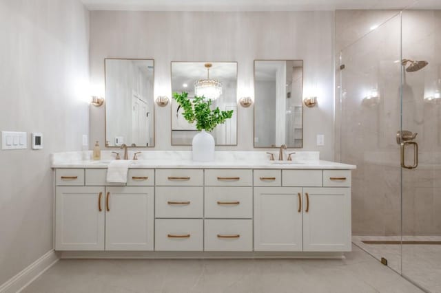 bathroom with double vanity, a stall shower, a sink, and baseboards