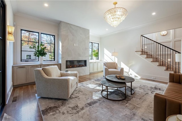 living room with ornamental molding, a fireplace, and light wood-style flooring