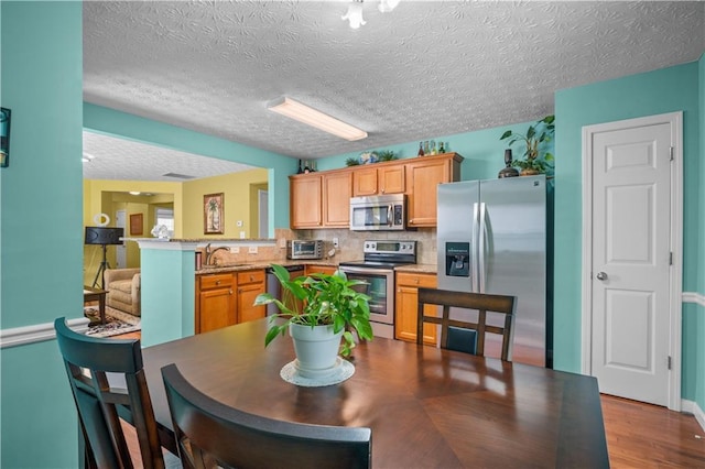 dining space featuring a textured ceiling, light wood-type flooring, and sink