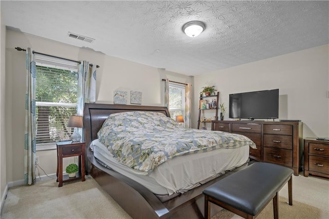 bedroom with a textured ceiling and light carpet