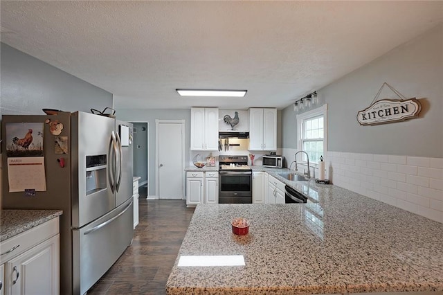 kitchen featuring a sink, a textured ceiling, stainless steel appliances, a peninsula, and white cabinets