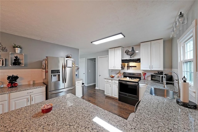 kitchen featuring ventilation hood, light stone counters, stainless steel fridge with ice dispenser, a sink, and electric stove