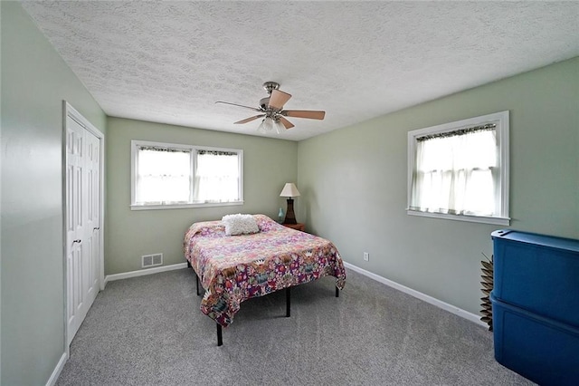 carpeted bedroom featuring baseboards, visible vents, a closet, and ceiling fan