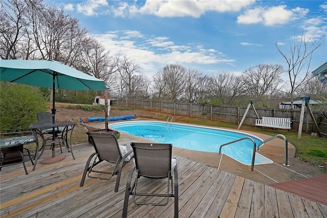 view of swimming pool with a wooden deck, a fenced in pool, and a fenced backyard