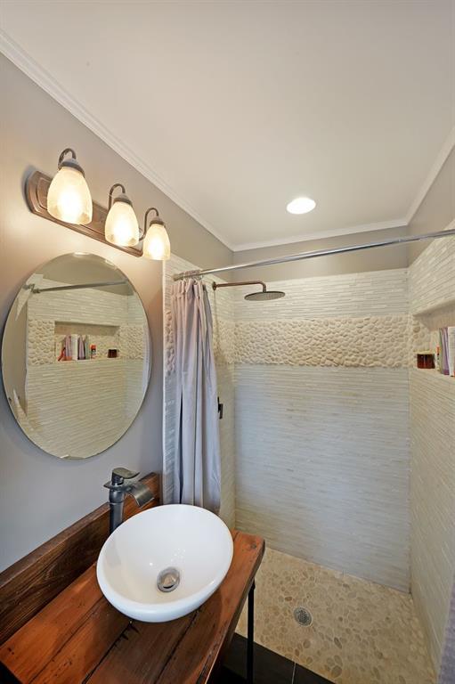 bathroom with tiled shower, ornamental molding, and vanity