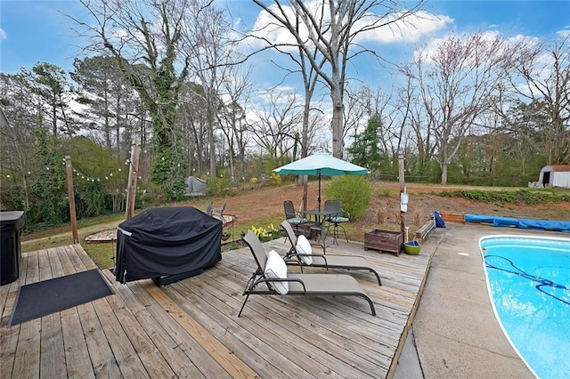 view of pool featuring a covered pool, a grill, a deck, and an outdoor fire pit