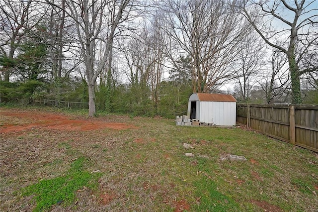 view of yard featuring an outbuilding, a storage shed, and fence