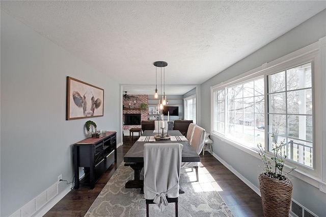 dining room with visible vents, baseboards, dark wood-type flooring, and a fireplace