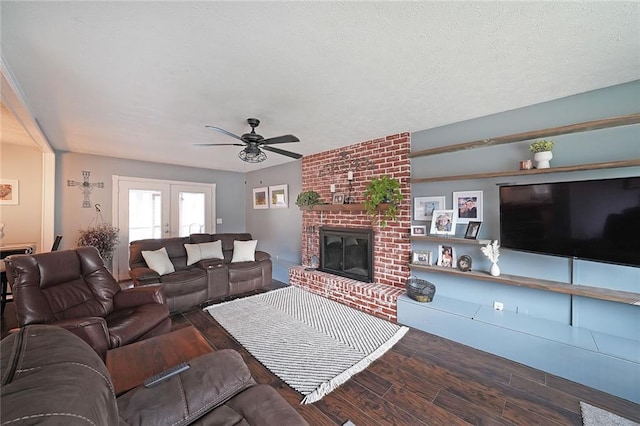 living area with a ceiling fan, wood finished floors, a fireplace, french doors, and a textured ceiling