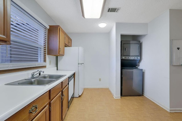 kitchen with stacked washer and clothes dryer, sink, a textured ceiling, stainless steel dishwasher, and electric panel