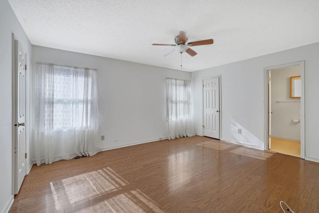 unfurnished bedroom featuring a textured ceiling, wood-type flooring, ceiling fan, and ensuite bathroom