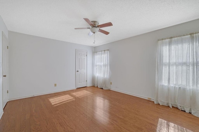 unfurnished room with plenty of natural light, a textured ceiling, ceiling fan, and light hardwood / wood-style flooring